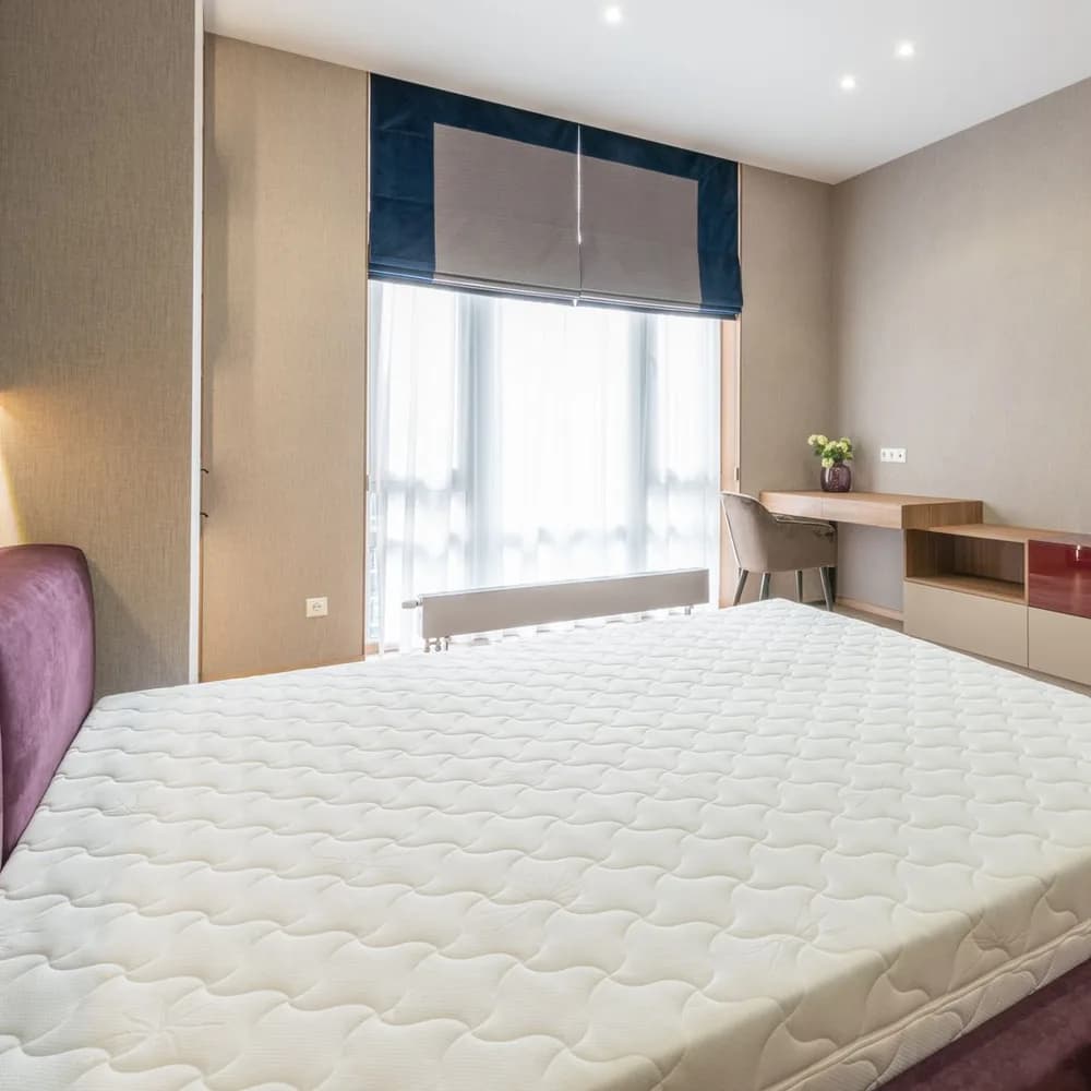 Colchón Queen blanco acolchado sobre una cama en un dormitorio moderno