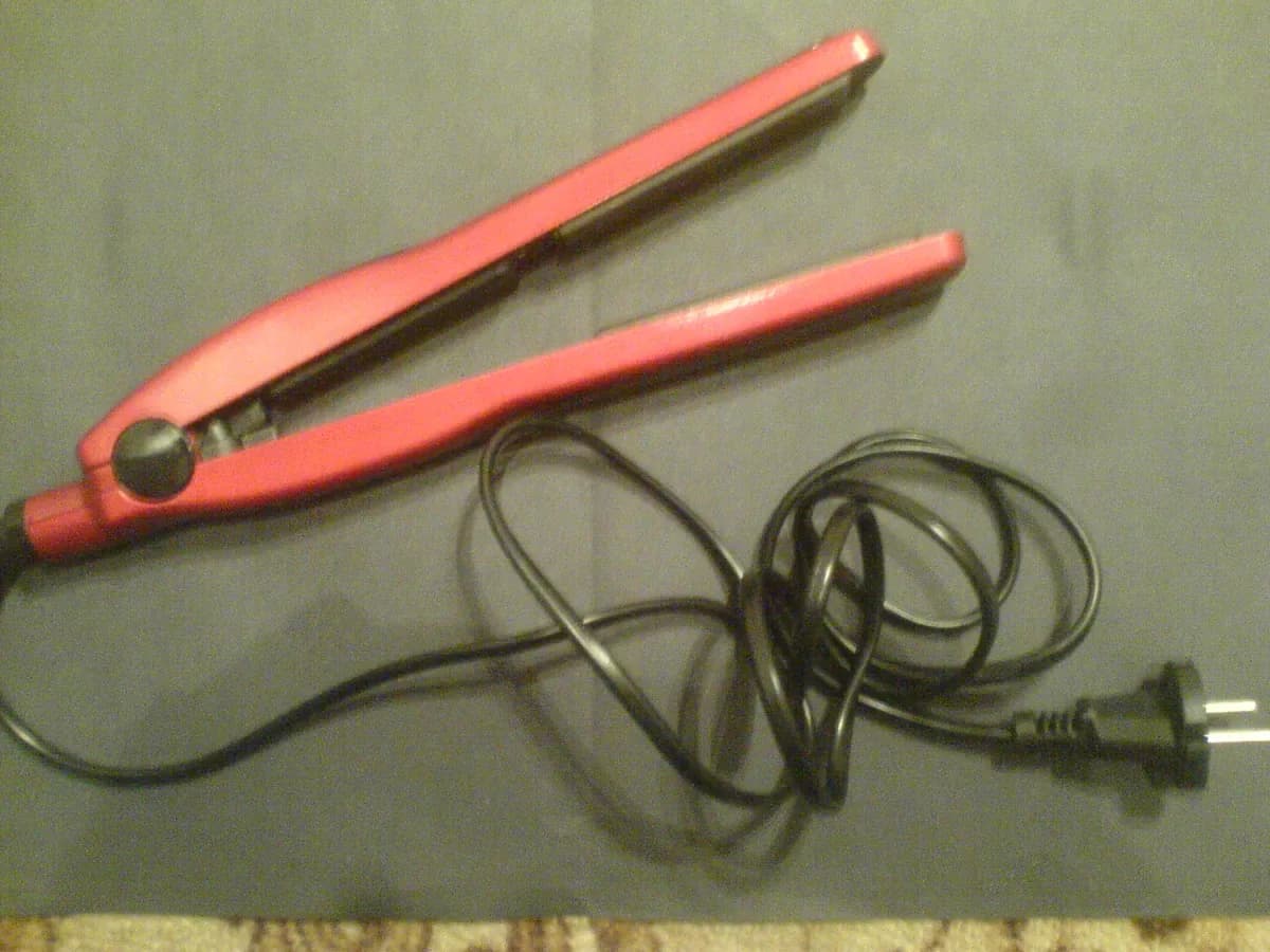 Plancha alisadora coral con cable sobre tela gris